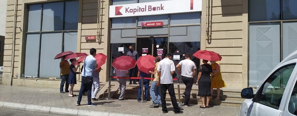 Kapital Bank filialların önündə müştəriləri günvurmadan qoruyur